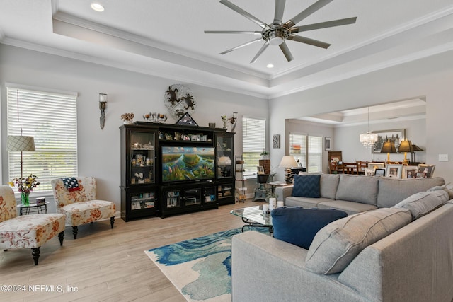 living room featuring a tray ceiling, light hardwood / wood-style flooring, and ornamental molding