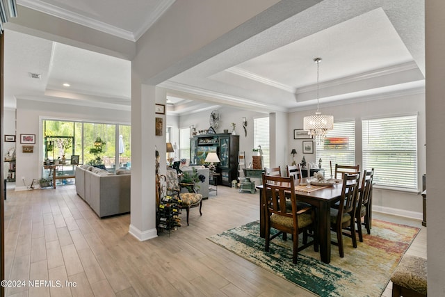 dining area with plenty of natural light, a raised ceiling, and ornamental molding