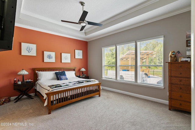 bedroom featuring light carpet, a tray ceiling, ceiling fan, and ornamental molding