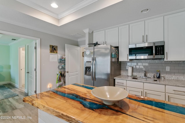 kitchen with white cabinets, crown molding, sink, and stainless steel appliances