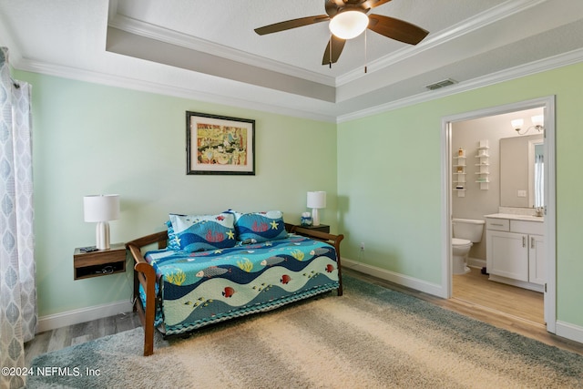 bedroom featuring ceiling fan, a raised ceiling, ornamental molding, and connected bathroom