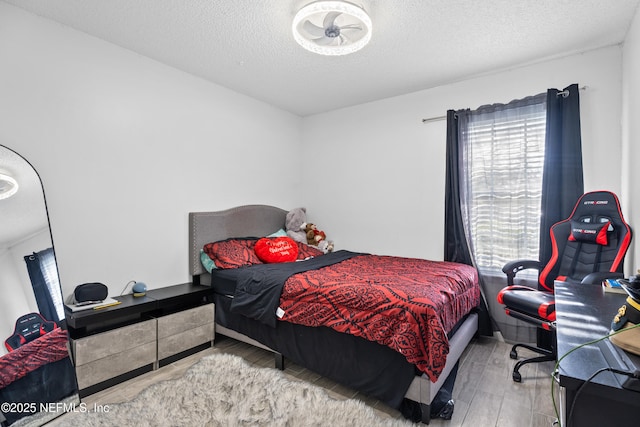 bedroom with light wood-type flooring and a textured ceiling