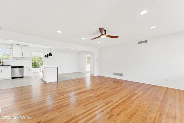 unfurnished living room featuring ceiling fan, light hardwood / wood-style floors, and sink