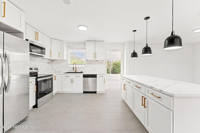 kitchen with light stone countertops, tasteful backsplash, stainless steel appliances, pendant lighting, and white cabinets