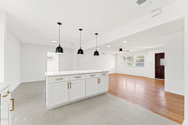 kitchen featuring pendant lighting, a center island, white cabinets, ceiling fan, and light hardwood / wood-style floors