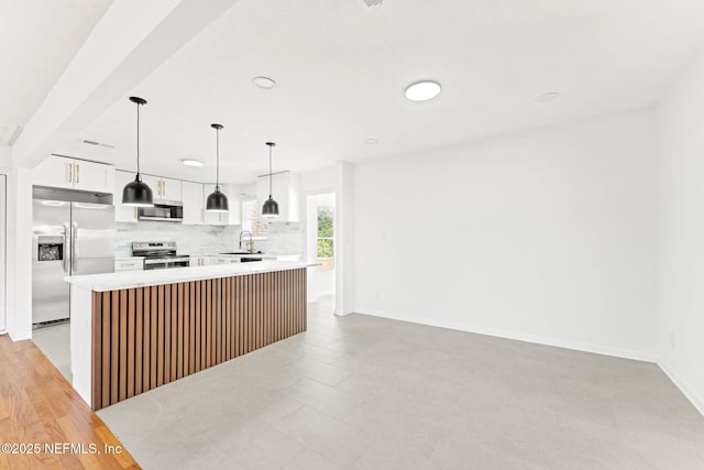 kitchen featuring sink, stainless steel appliances, a kitchen island, decorative light fixtures, and white cabinets