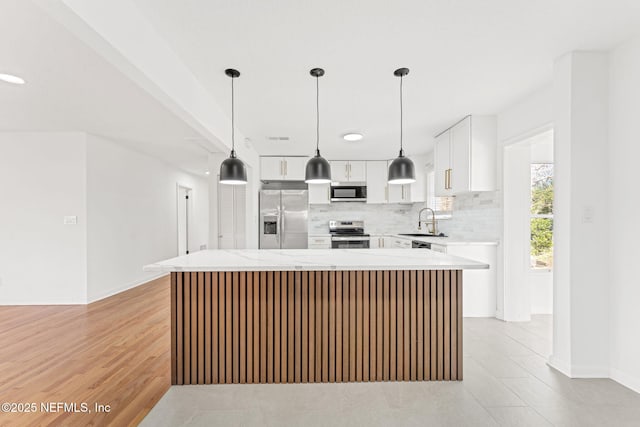 kitchen with a center island, hanging light fixtures, sink, appliances with stainless steel finishes, and white cabinetry