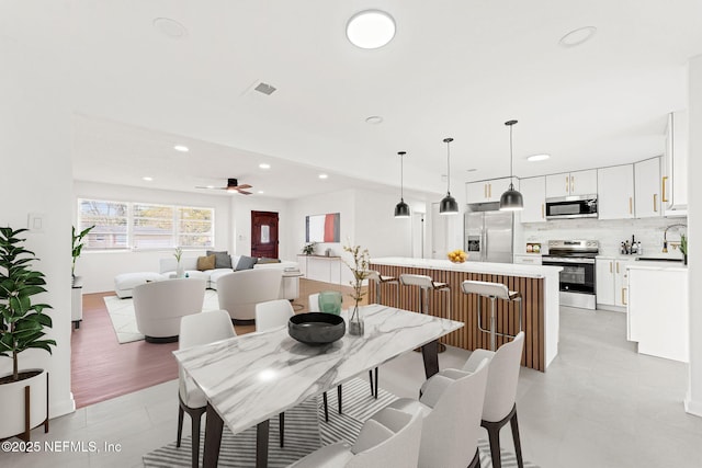 dining space featuring ceiling fan and sink