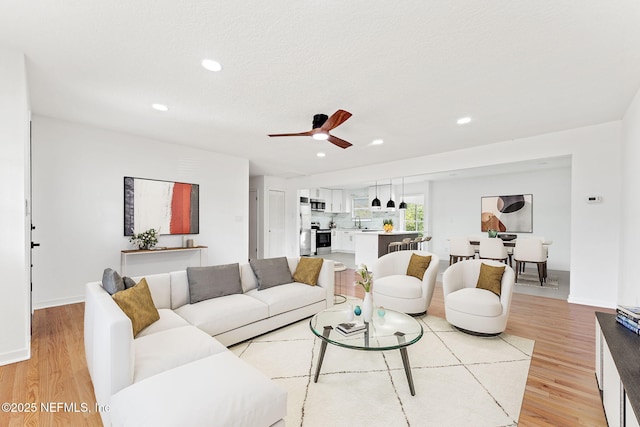 living room with light hardwood / wood-style floors, ceiling fan, and sink