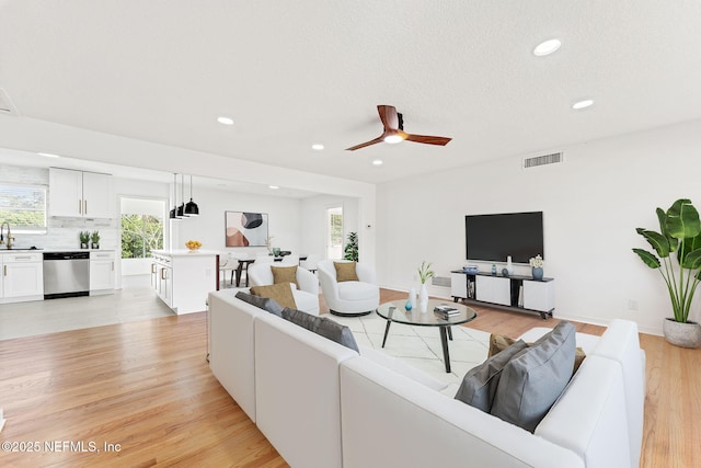 living room featuring ceiling fan, light wood-type flooring, and sink