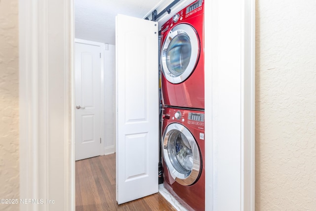 laundry room with wood-type flooring, a textured ceiling, and stacked washer and clothes dryer