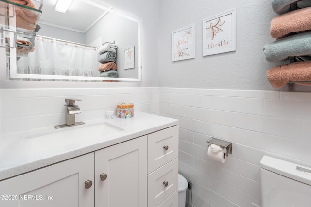 bathroom featuring vanity, tile walls, and toilet