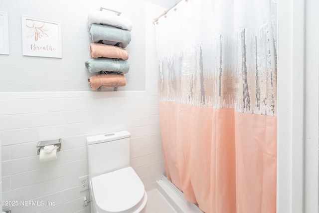 bathroom with curtained shower, tile walls, and toilet