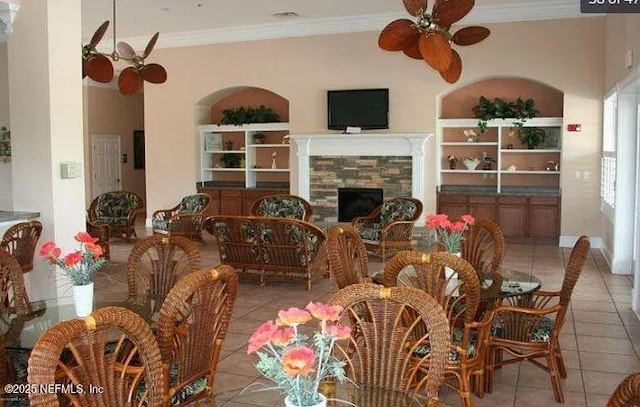 dining space with ceiling fan, a fireplace, light tile patterned floors, and crown molding