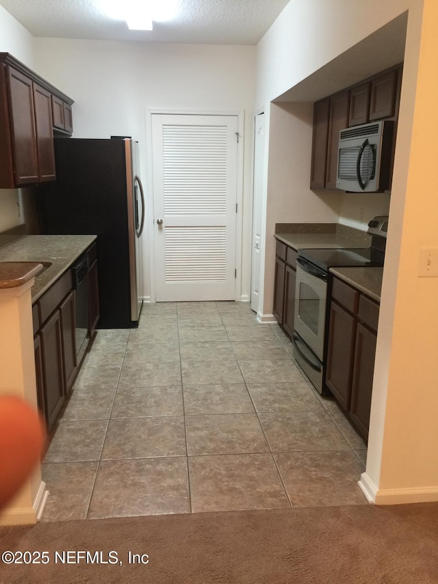 kitchen featuring dark brown cabinetry, light tile patterned flooring, and black appliances