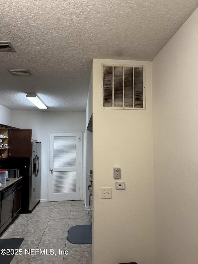 kitchen with dishwasher, stainless steel refrigerator with ice dispenser, a textured ceiling, and light tile patterned flooring