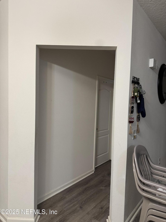 hallway with a textured ceiling and dark hardwood / wood-style floors