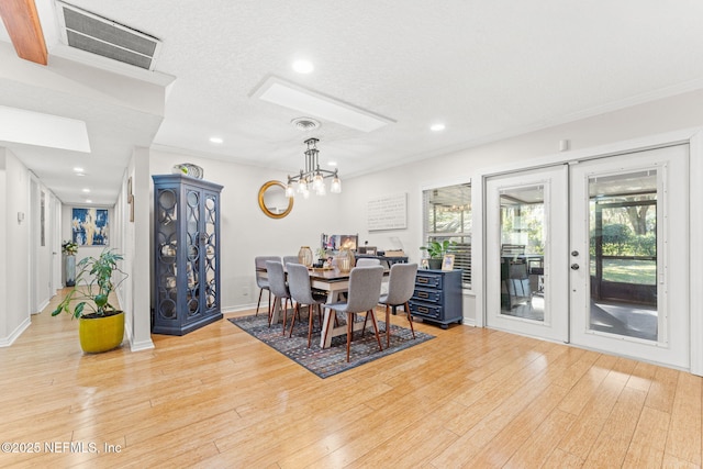 dining area featuring a notable chandelier, french doors, a textured ceiling, and light hardwood / wood-style flooring