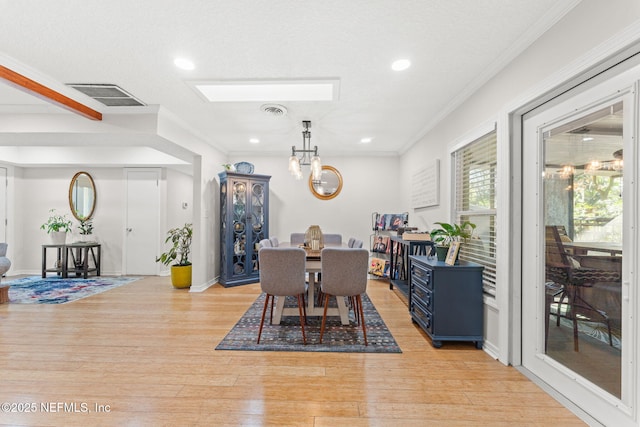 dining room with crown molding, light hardwood / wood-style floors, and a textured ceiling