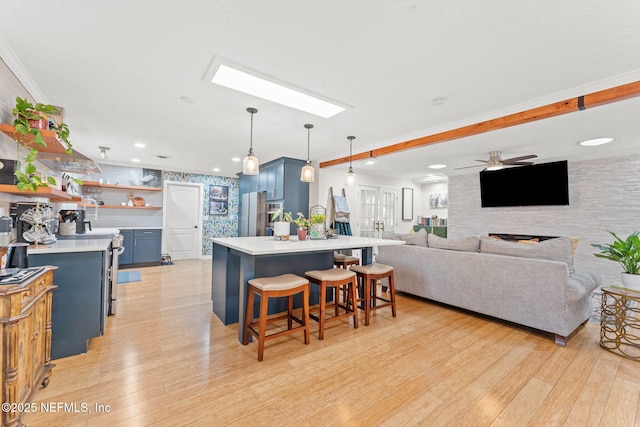 kitchen featuring ceiling fan, blue cabinets, a breakfast bar, and light hardwood / wood-style flooring