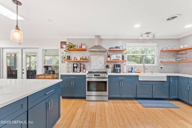 kitchen featuring wall chimney exhaust hood, blue cabinets, pendant lighting, stainless steel range with electric stovetop, and decorative backsplash