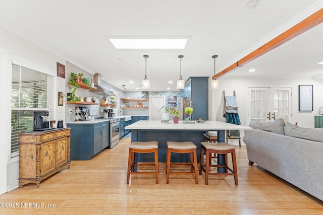 kitchen featuring a breakfast bar, hanging light fixtures, stainless steel electric range oven, blue cabinetry, and light hardwood / wood-style floors