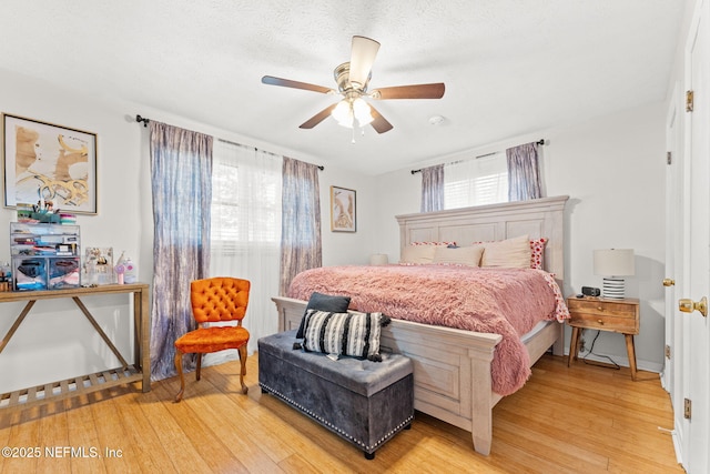 bedroom with a textured ceiling, light hardwood / wood-style floors, and ceiling fan