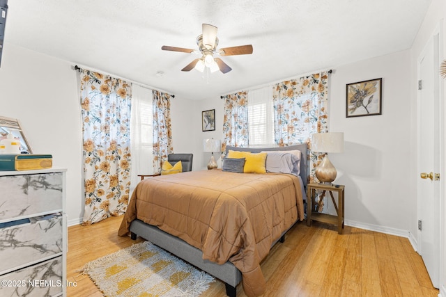 bedroom featuring ceiling fan, light hardwood / wood-style floors, and a textured ceiling