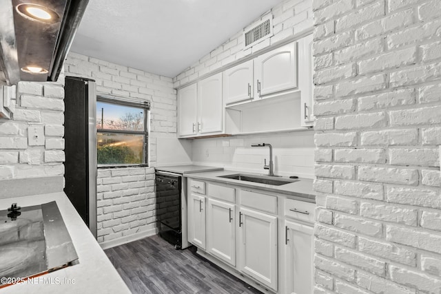 kitchen with sink, dark hardwood / wood-style floors, black dishwasher, brick wall, and white cabinets