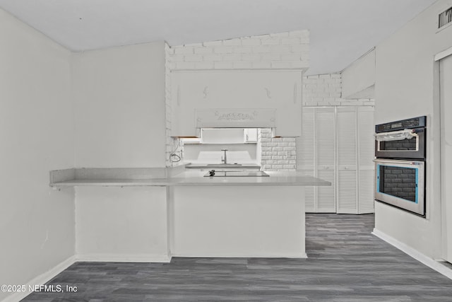 kitchen featuring dark wood-type flooring, white cabinetry, kitchen peninsula, double oven, and black electric stovetop