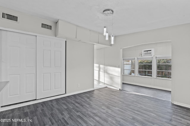 interior space with dark hardwood / wood-style flooring, a wall mounted AC, and a closet