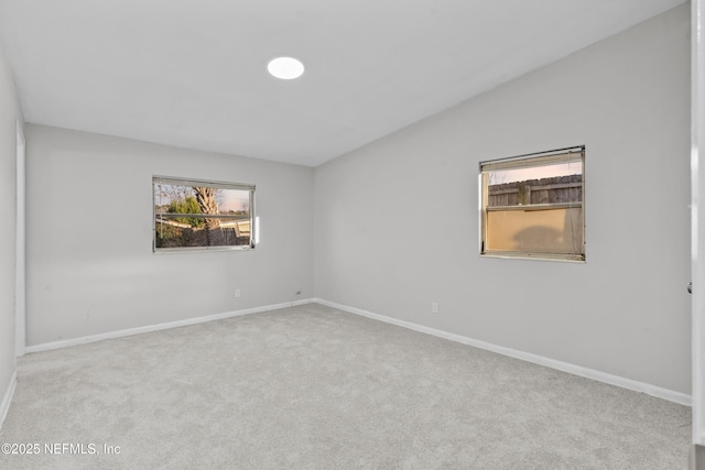 carpeted empty room with plenty of natural light and vaulted ceiling