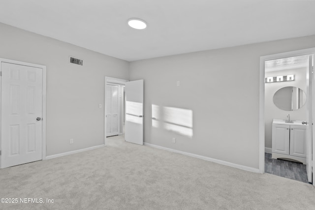 unfurnished bedroom with connected bathroom, sink, and light carpet