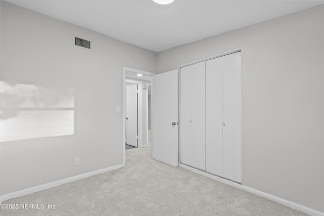 unfurnished bedroom featuring light carpet and a closet