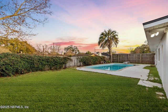 pool at dusk with a lawn and a patio