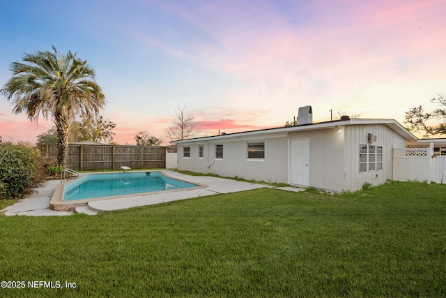 pool at dusk with a lawn and a patio area