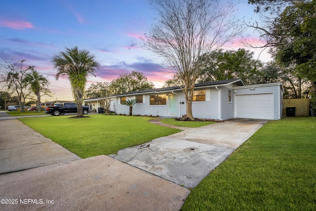 ranch-style home featuring a lawn and a garage