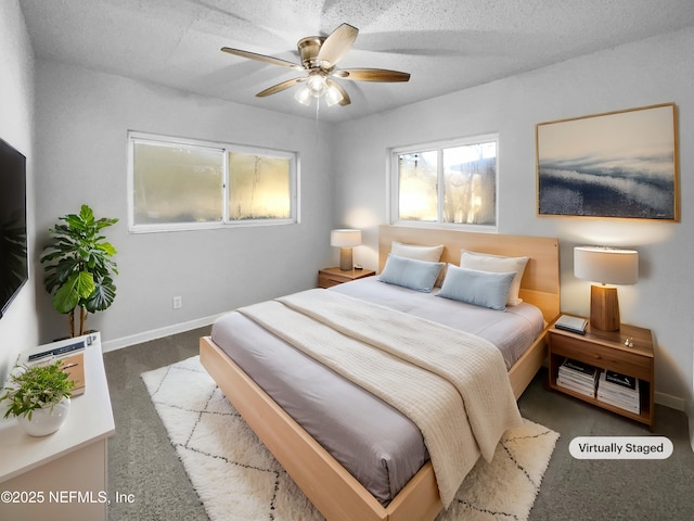 bedroom with ceiling fan, dark carpet, and a textured ceiling