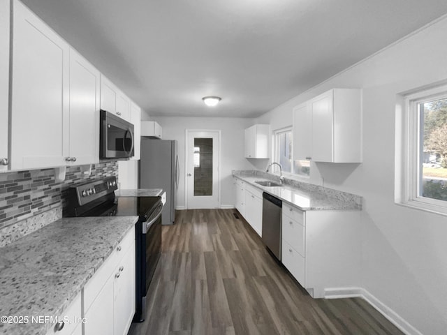 kitchen with white cabinets, appliances with stainless steel finishes, light stone counters, and sink