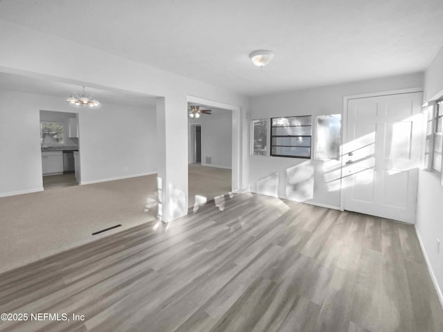 unfurnished living room with carpet flooring and ceiling fan with notable chandelier