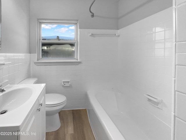 full bathroom featuring tile walls, toilet, vanity, bathtub / shower combination, and hardwood / wood-style flooring