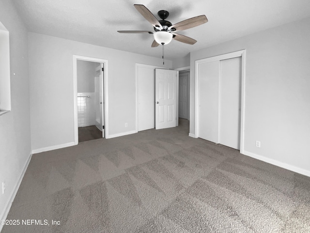 unfurnished bedroom with ensuite bathroom, dark carpet, and ceiling fan