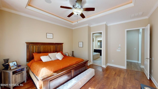 bedroom with ensuite bath, a raised ceiling, ceiling fan, crown molding, and hardwood / wood-style floors