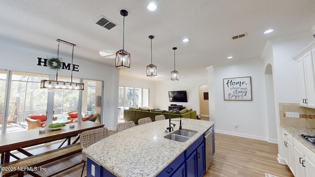 kitchen featuring blue cabinetry, light stone countertops, sink, an island with sink, and white cabinets