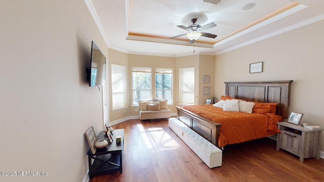 bedroom featuring ceiling fan, a raised ceiling, wood-type flooring, and crown molding