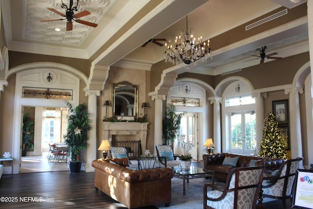 living room featuring ornate columns, crown molding, dark wood-type flooring, and a chandelier