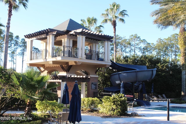 view of front of house with a balcony and a swimming pool