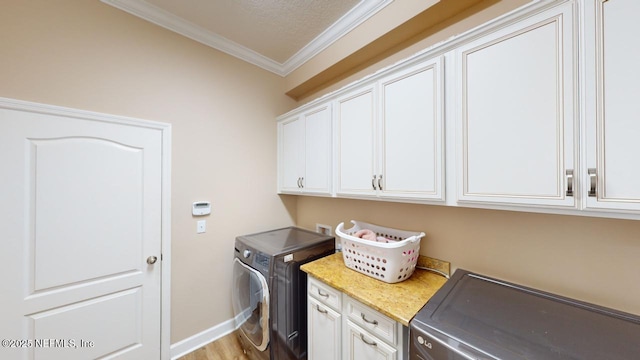 laundry room featuring independent washer and dryer, crown molding, cabinets, and light hardwood / wood-style floors