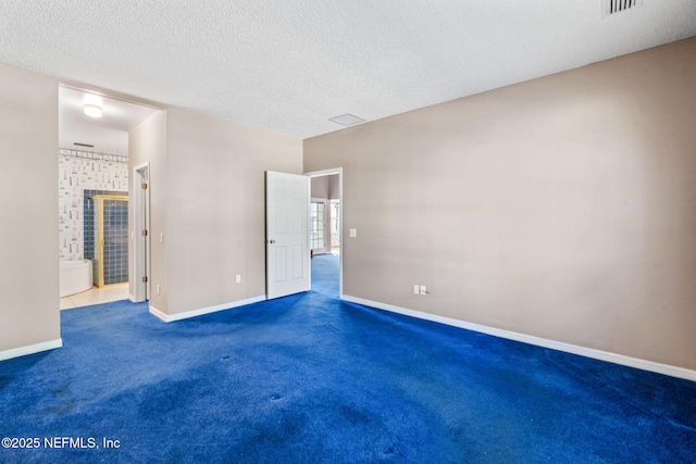 unfurnished bedroom featuring ensuite bath, a textured ceiling, and carpet flooring