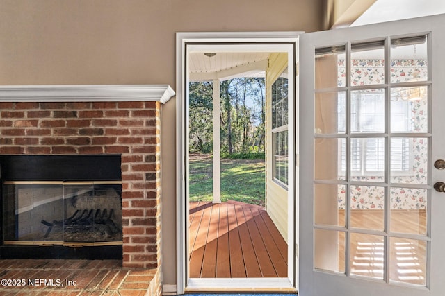 doorway to outside with a brick fireplace and plenty of natural light